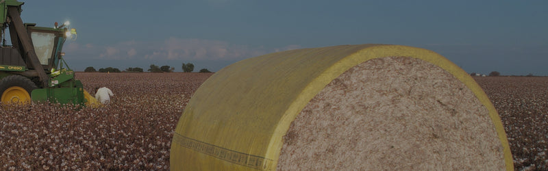 Tractor in a field with a large bale of hay.