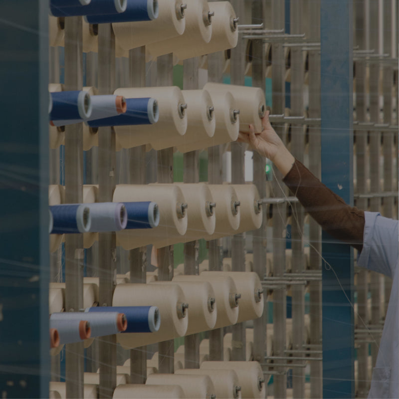 Person adjusting spools of thread on a textile machine