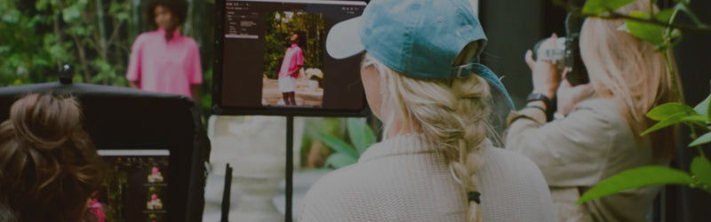 Person using a smartphone to view photos on a screen outdoors with greenery.