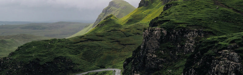 Scenic view of green hills and rocky outcrops under a cloudy sky