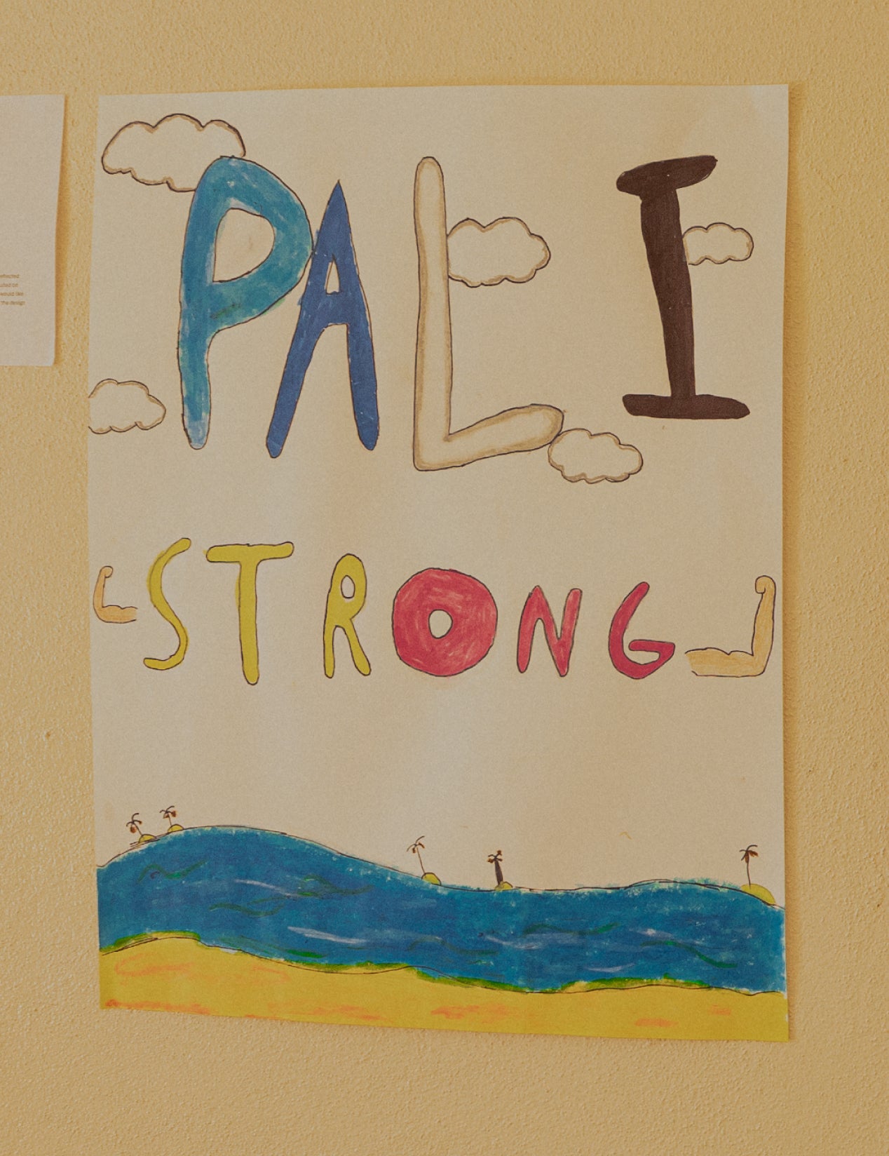 Handmade poster with 'PALL STRONG' text and a beach scene on a beige wall.